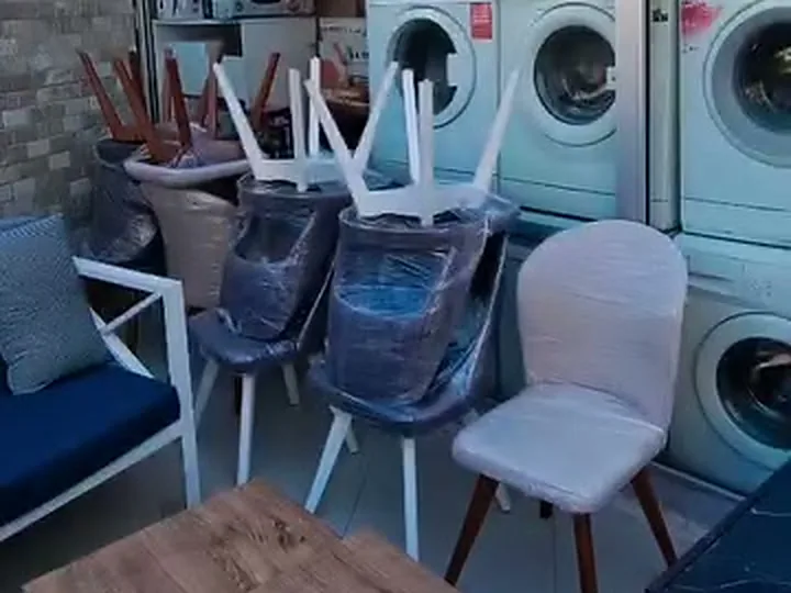 Berat Spot Buca mağazasında sıralanmış ikinci el çamaşır makineleri ve sandalyeler