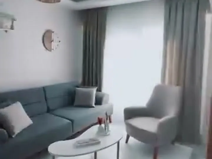Gri köşe koltuk, berjer ve oval orta sehpa ile döşenmiş salon